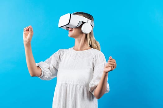 Girl smells flower while wearing VR glasses at blue background. Happy woman with VR goggle enjoy looking nature hologram while connection with visual reality world. Technology innovation. Contraption.