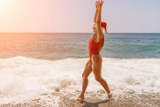 A woman in Santa hat on the seashore, dressed in a red swimsuit. New Year's celebration in a hot country