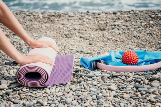 Young woman with long hair in white swimsuit and boho style braclets practicing outdoors on yoga mat by the sea on a sunset. Women's yoga fitness routine. Healthy lifestyle, harmony and meditation