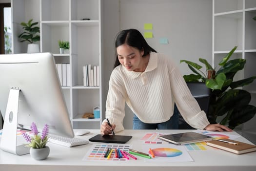 Female designer working in graphic design on computer Sit and choose colors and work intently in your office..