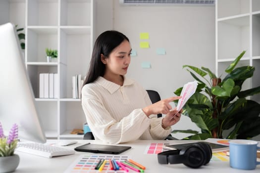 Female designer working in graphic design on computer Sit and choose colors and work intently in your office..