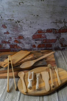 various types of wooden kitchen utensils on wooden cutting boards with a brick wall backing