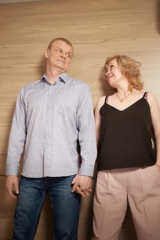 Loving adult couple communicates and embraces privately in the living room or in hotel. Woman is wearing business formal suit and man is wearing jeans and a shirt, indicating a close relationship