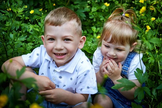 Cute kids in flowers in nature. Funny Boy and girl in grass. A good environment means Healthy, happy children