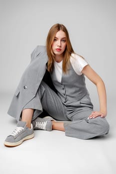 Young Woman in a Gray Suit Sitting on the Floor in Studio portrait