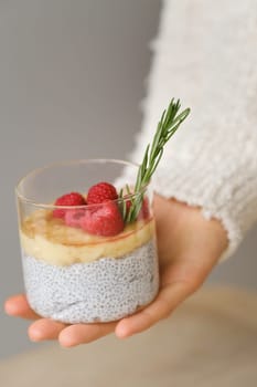 Delicious passion fruit and banana smoothie with raspberries in a glass on your hand.