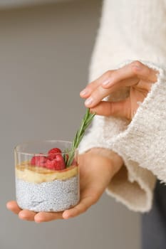 Delicious passion fruit and banana smoothie with raspberries in a glass on your hand.