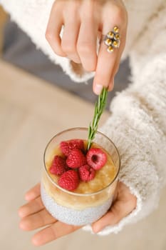 Delicious passion fruit and banana smoothie with raspberries in a glass on your hand.