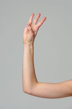 Female hand gesturing numbers on gray background close up