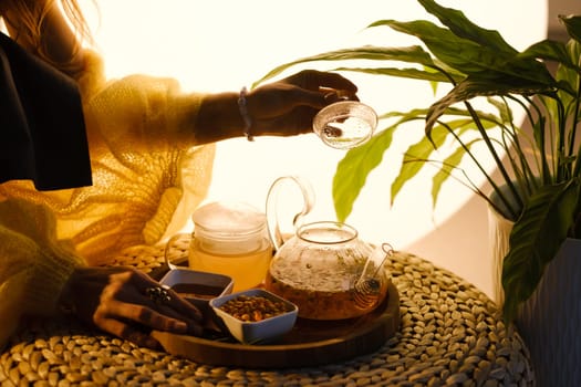 A teapot with sea buckthorn tea, honey and a plate with sea buckthorn on a tray.