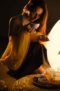 A young girl conducts an evening tea drinking procedure indoors. Relaxing tea party.