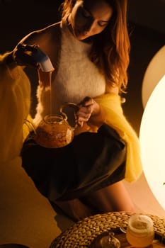 A young girl conducts an evening tea drinking procedure indoors. Relaxing tea party.