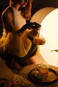 A young girl conducts an evening tea drinking procedure indoors. Relaxing tea party.