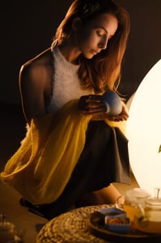 A young girl conducts an evening tea drinking procedure indoors. Relaxing tea party.