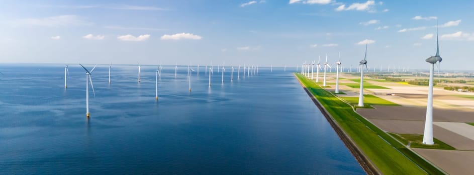 A large body of water in the Netherlands Flevoland is surrounded by numerous wind mills, their blades spinning gracefully in the wind.