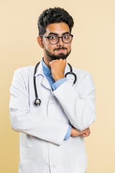 Sad Indian young doctor cardiologist man tired bored exhausted indifferent expression, not interested in communication talk, displeasure. Arabian apothecary pharmacy guy isolated on beige background