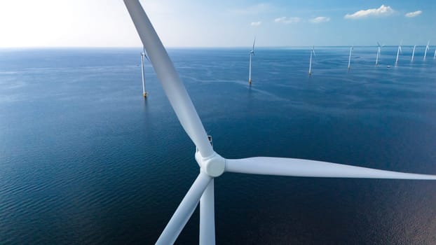 Towering windmill turbines are intricately placed in the vast ocean expanse of the Netherlands Flevoland region, harnessing the power of the wind to generate clean energy.