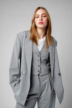 Woman in Gray Suit and White Shirt posing in studio on gray background