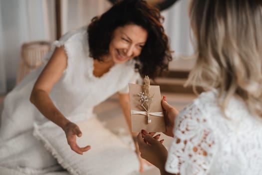 A woman in white clothes passes an envelope with a wish to another woman. The concept of the women's circle.