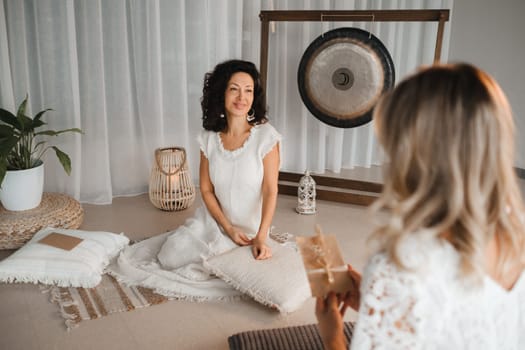 A woman in white clothes passes an envelope with a wish to another woman. The concept of the women's circle.