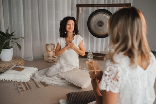 A woman in white clothes passes an envelope with a wish to another woman. The concept of the women's circle.