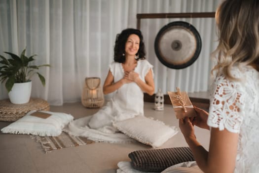 A woman in white clothes passes an envelope with a wish to another woman. The concept of the women's circle.