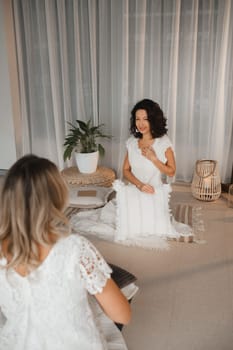 Two women practice yoga sitting opposite each other.