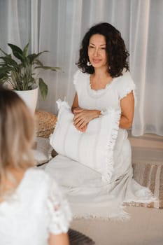 Two women practice yoga sitting opposite each other.