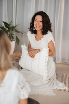 Two women practice yoga sitting opposite each other.