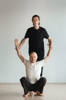 two young athletes practice yoga in the gym. Joint training, indoors, studio. The concept of a healthy lifestyle.