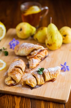 Sweet pastries, puff pastries with pears, on a wooden table .