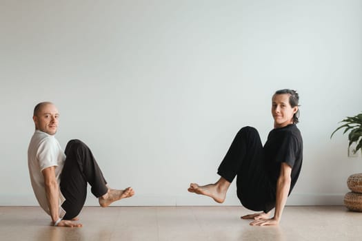 two young athletes practice yoga in the gym. Joint training, indoors, studio. The concept of a healthy lifestyle.