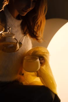 A young girl conducts an evening tea drinking procedure indoors. Relaxing tea party.