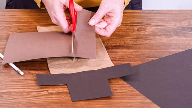 Step by step. Teacher guides online class through making a paper puppet from a brown bag, creatively using a wooden surface as a workspace.