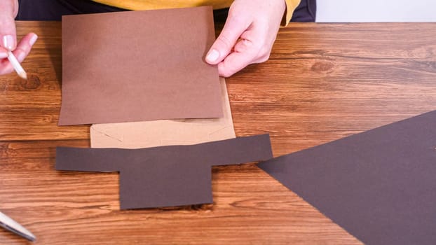 Step by step. Teacher guides online class through making a paper puppet from a brown bag, creatively using a wooden surface as a workspace.