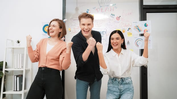 Successful caucasian business team posing victory posing victory pose to celebrate successful idea at creative business meeting in front of glass board. Unity and teamwork concept. Immaculate.