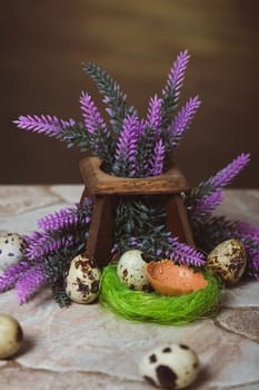 Quail eggs near the nest and lavender flowers on a stone background. Easter Postcard