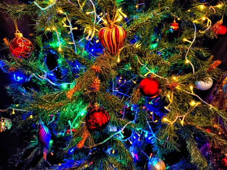 Close-up of Christmas tree with colorful decorations and twinkling lights. Festive Christmas Tree Adorned With Ornaments and Lights