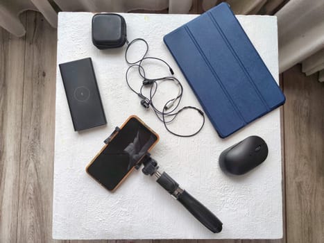 A set of useful blogger devices. A neatly organized desk featuring a smartphone, earphones, and various tech gadgets