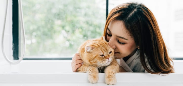 Enjoying a luxurious bath, a woman's contented smile reflects her deep connection with her Scottish Fold cat, exemplifying the bond between owner and pet in their cozy bathroom.