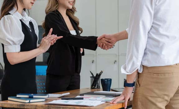 Successful business negotiation, handshake of two businessmen shaking hands with partners celebrating the successful completion of a deal in office conference room..