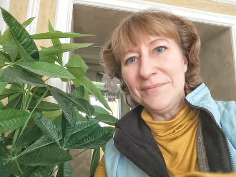 Portrait of cute blonde girl indoors. Funny middle-aged woman posing and taking selfie indoors