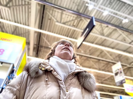 Middle-Aged Woman Shopping at a Warehouse Store. Woman browsing in large retail store aisle