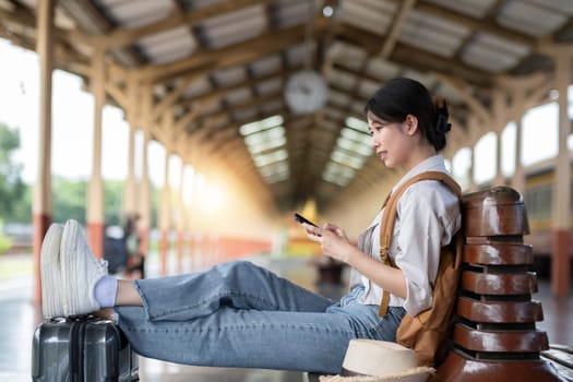 Young female traveler carrying a backpack waits for the train at the train station to travel alone..