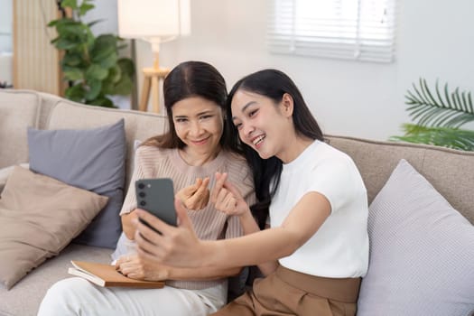 Mother and adult daughter sitting on the sofa together, mother and daughter talking relaxing on weekend together.