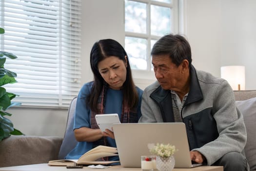 married retired senior couple checking and calculate financial billing together on sofa.