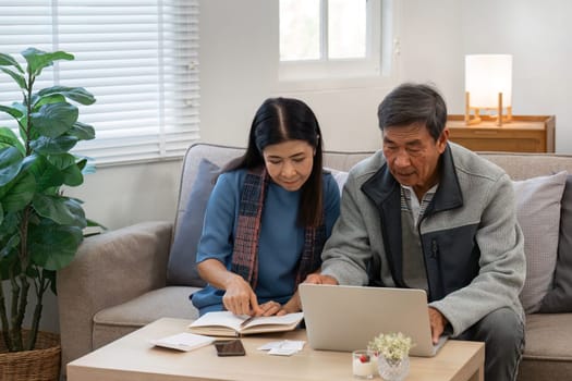 married retired senior couple checking and calculate financial billing together on sofa.