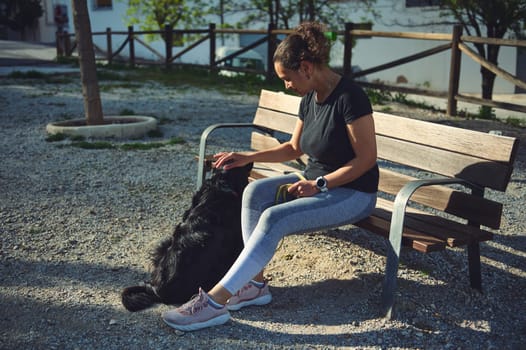 Happy young woman stroking her dog while walking on leash on the nature. Pets concept. People and domestic animals. Healthy active lifestyle concept