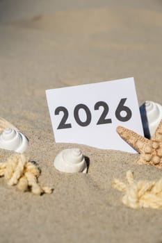 2026 text start new year symbol on paper greeting card on background of starfish summer vacation decor. Sandy beach sun coast. Holiday concept postcard. Getting away Travel Business concept