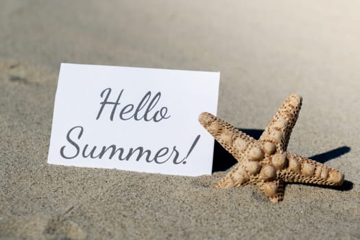 HELLO SUMMER text on paper greeting card on background of starfish seashell summer vacation decor. Sandy beach sun coast. Holiday concept postcard. Getting away Travel Business concept
